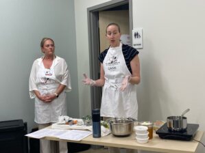 two women standing behind a cooking demonstration table