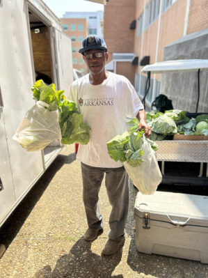 a man is carrying bags overflowing with leafy vegetables