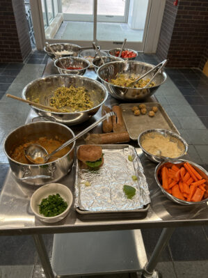 picture of a prep table in the kitchen. Large stainless steel bowls are filled with different ingredients.