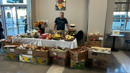 Man standing behind a table that is covered with fresh vegetables and fruit