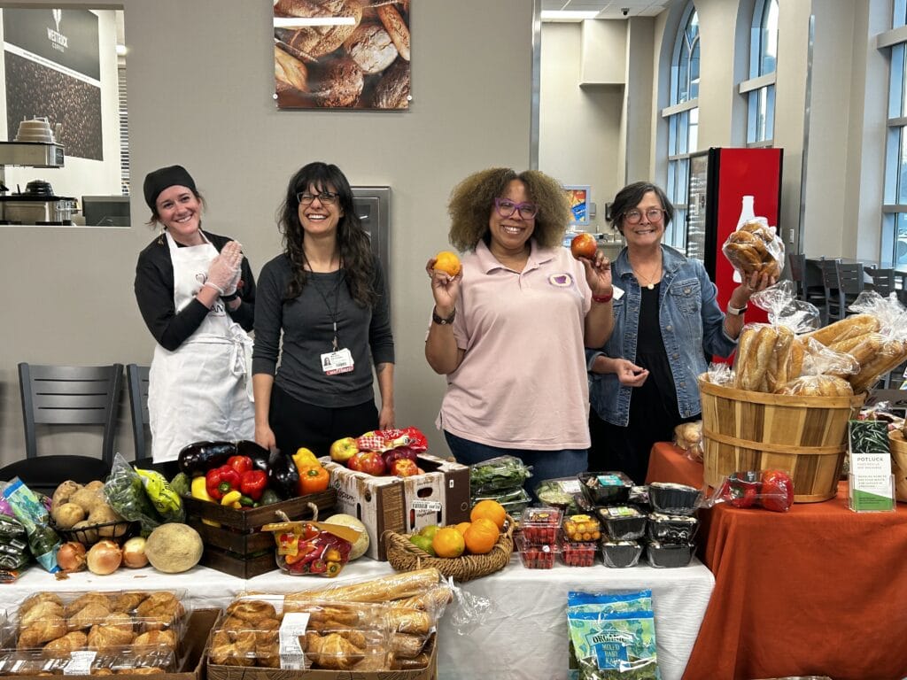 Women posing by a table loaded with fresh fruit