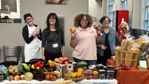 Women posing by a table loaded with fresh fruit