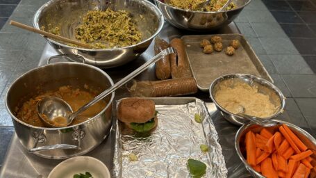 picture of a prep table in the kitchen. Large stainless steel bowls are filled with different ingredients.